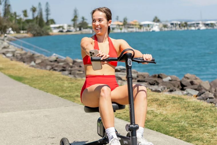Woman riding an Igofor folding mobility scooter along a waterfront path